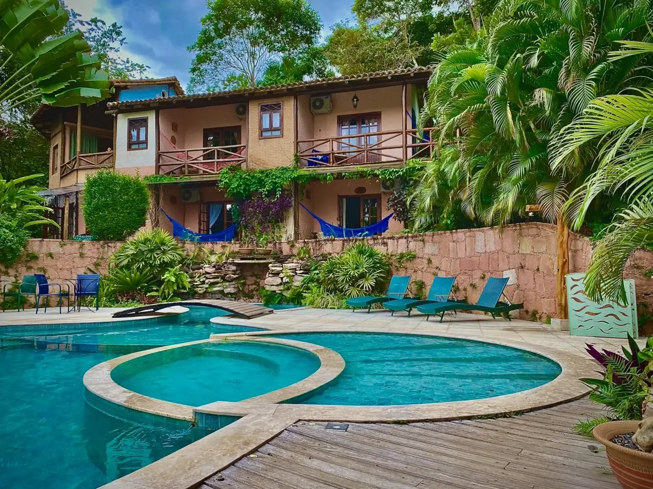 Piscina, acomodações e jardins tropicais da Pousada Vila Serrano