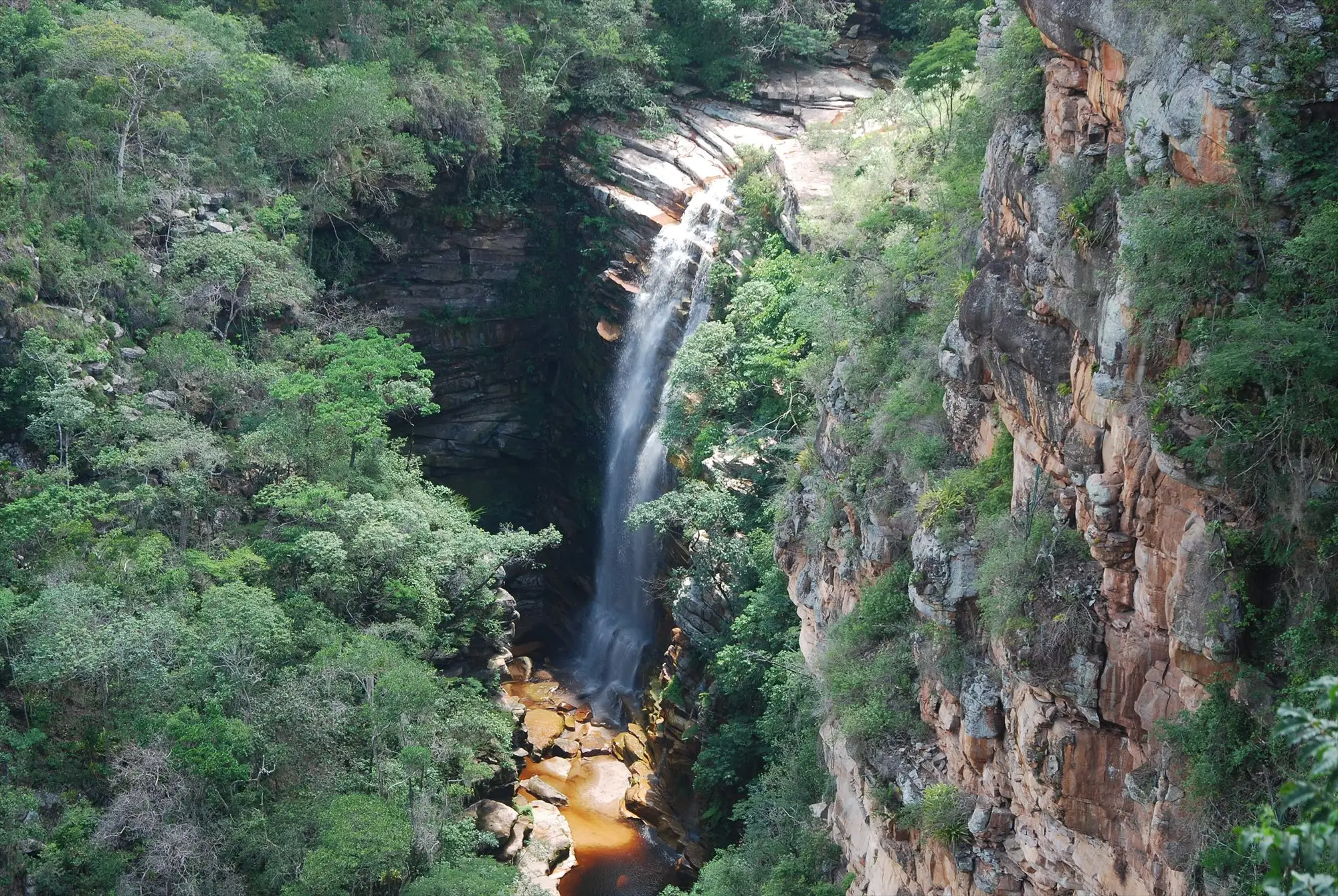 Cachoeira entre paredões e vegetação na Chapada Diamantina
