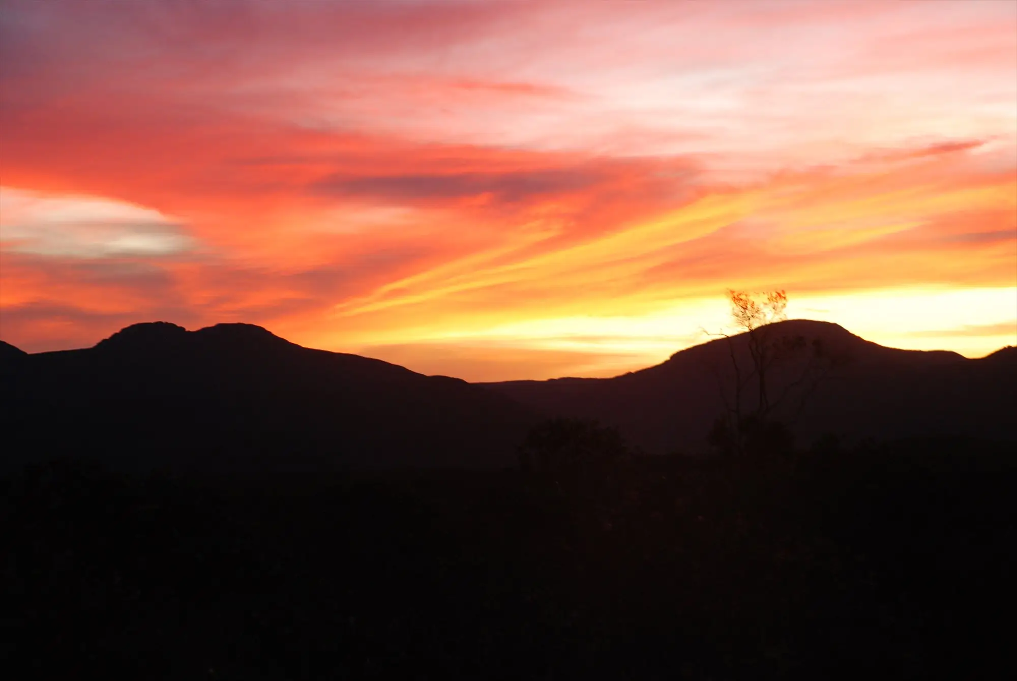 Pôr do sol alaranjado atrás das serras da Chapada Diamantina