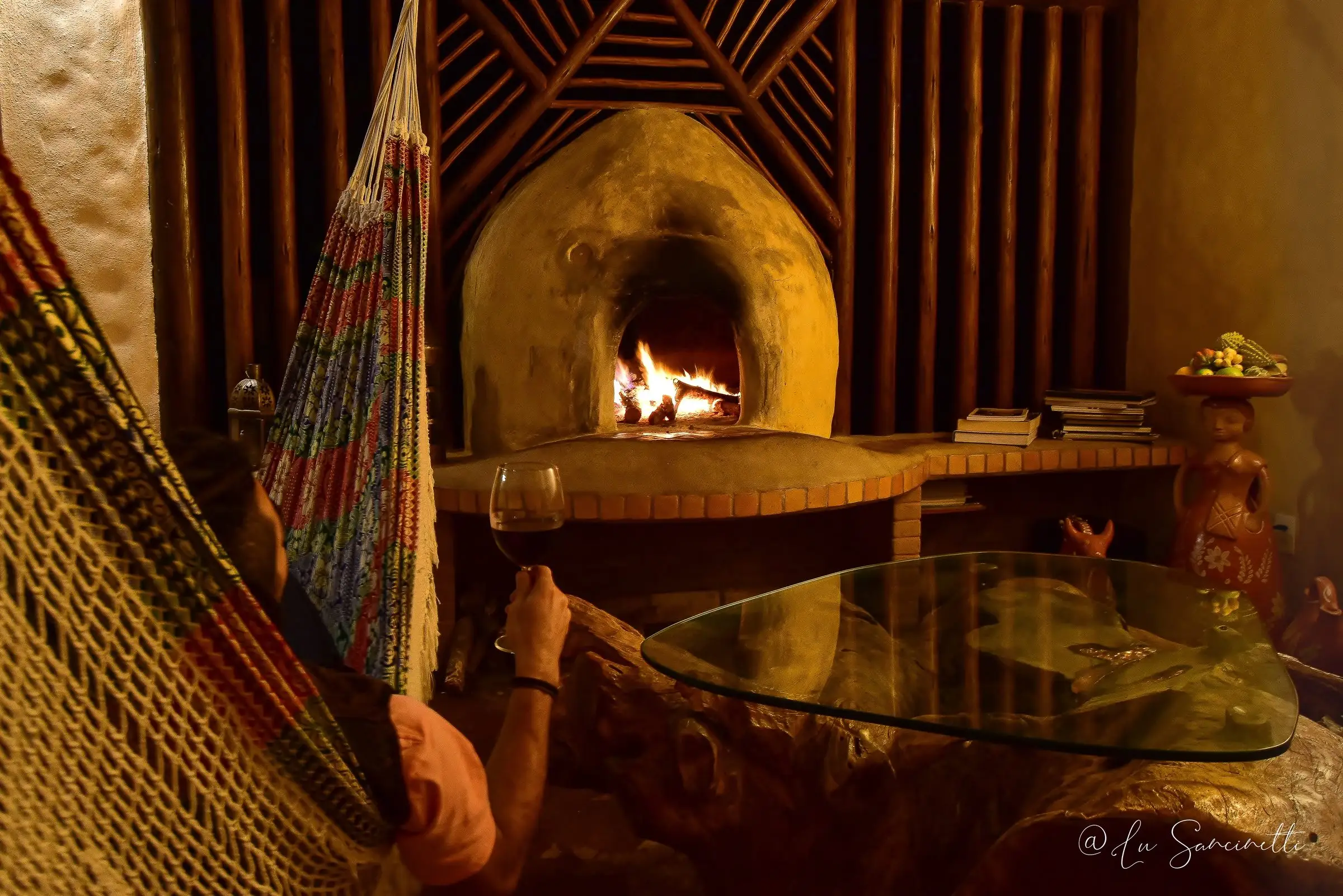 Guest in a hammock beside a lit fireplace