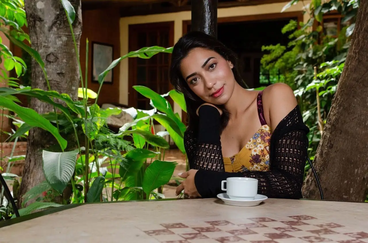 Guest with a cup of coffee at a table among garden plants